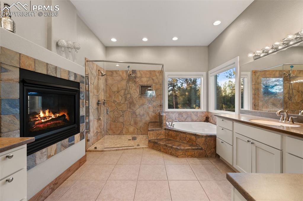 Image 19 of 50: Master bathroom with fireplace and heated towel rack and warming above ligh