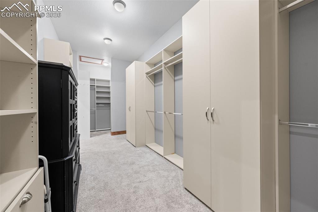 Image 22 of 50: Enormous walk in closet with built in custom closet shelves and racks!