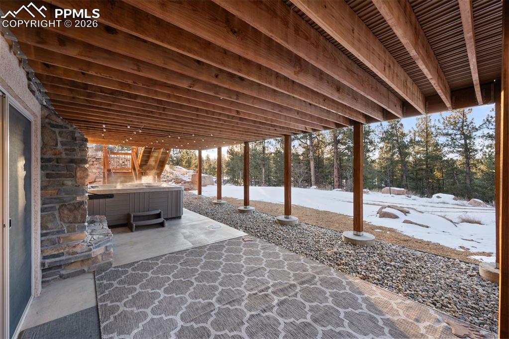 Image 37 of 50: Back covered patio with fireplace, hot tub and covered patio.