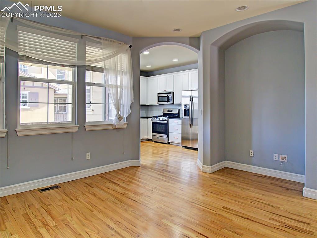 Image 10 of 27: Kitchen with stainless steel appliances, white cabinets, light wood-type fl