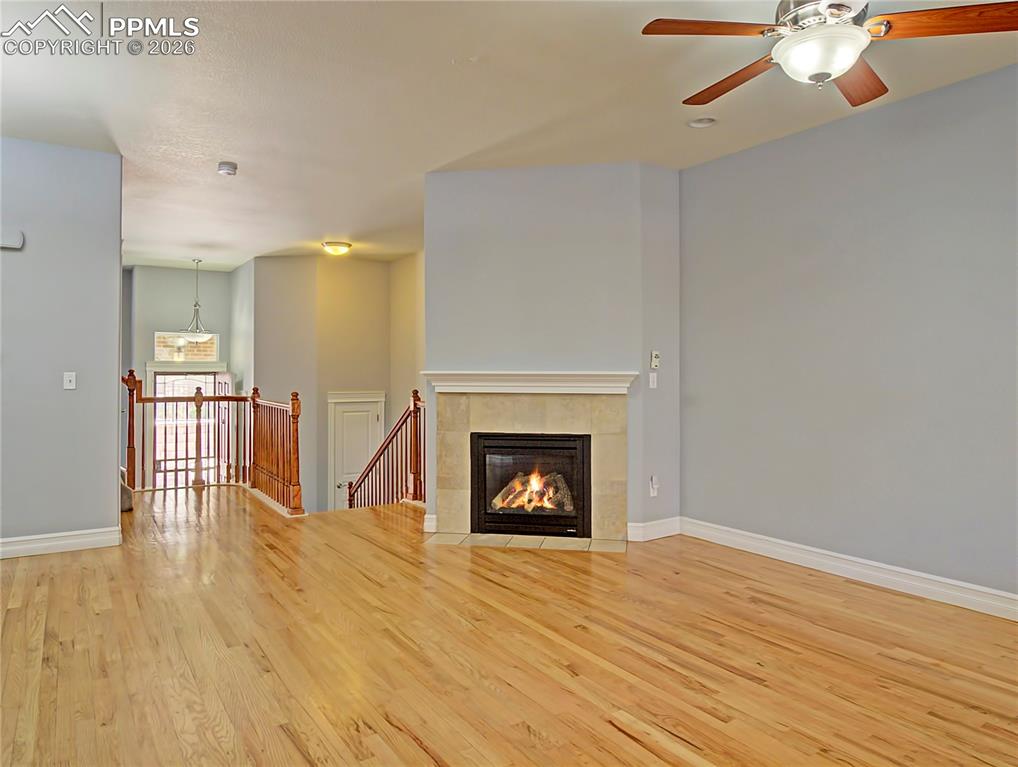 Image 11 of 27: Unfurnished living room with a tiled fireplace, light wood-style flooring, 