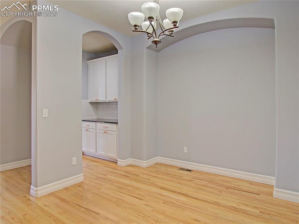 Image 8 of 27: Unfurnished dining area featuring a chandelier, light wood-style flooring, 