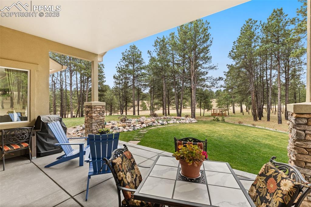 Image 4 of 41: Covered patio overlooking lush grass, an 8,000 gallon pond and backs to ope