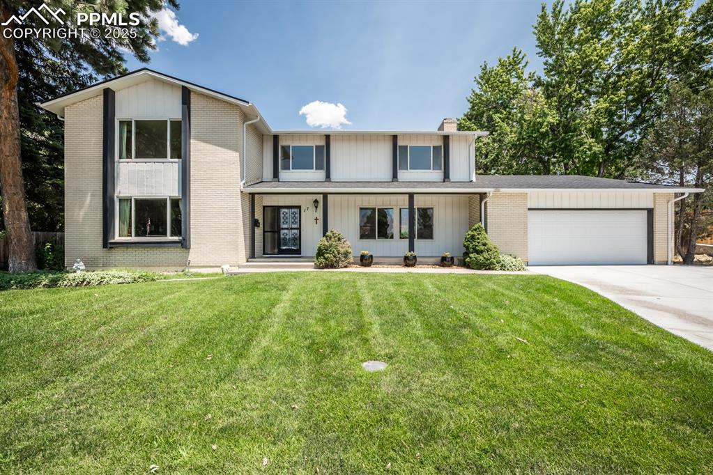Caption: View of front of property featuring a porch, concrete driveway, an attached garage, and a front lawn