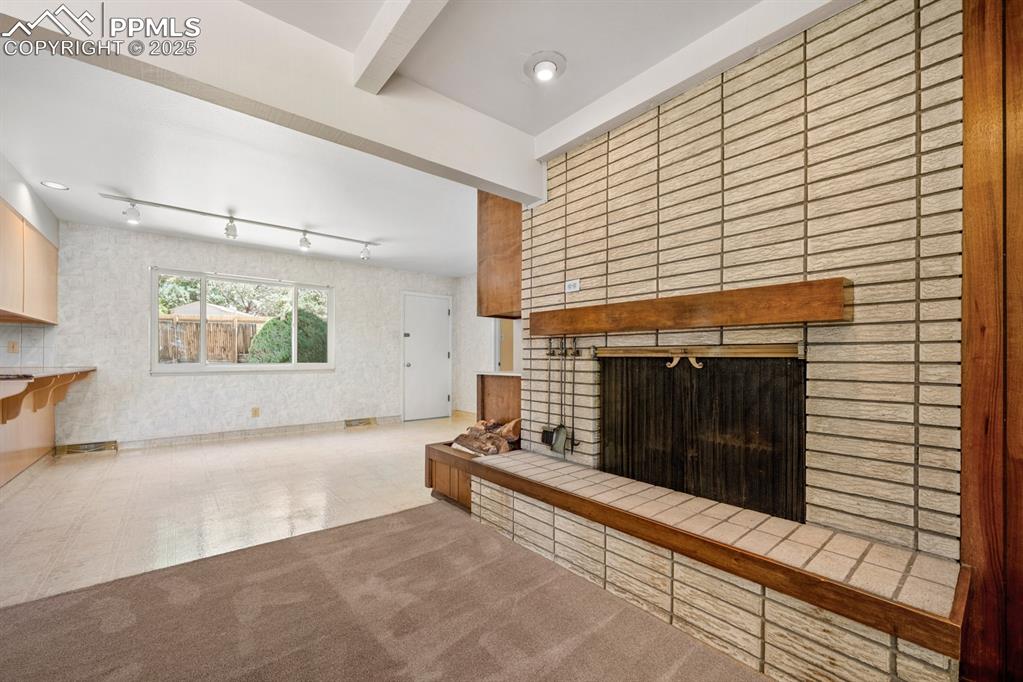 Image 10 of 50: Unfurnished living room with a fireplace, beamed ceiling, tile patterned fl