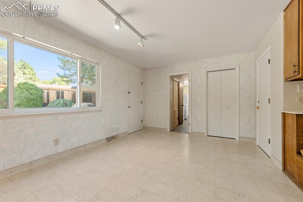 Image 11 of 50: Unfurnished bedroom featuring light floors, a closet, track lighting, ensui