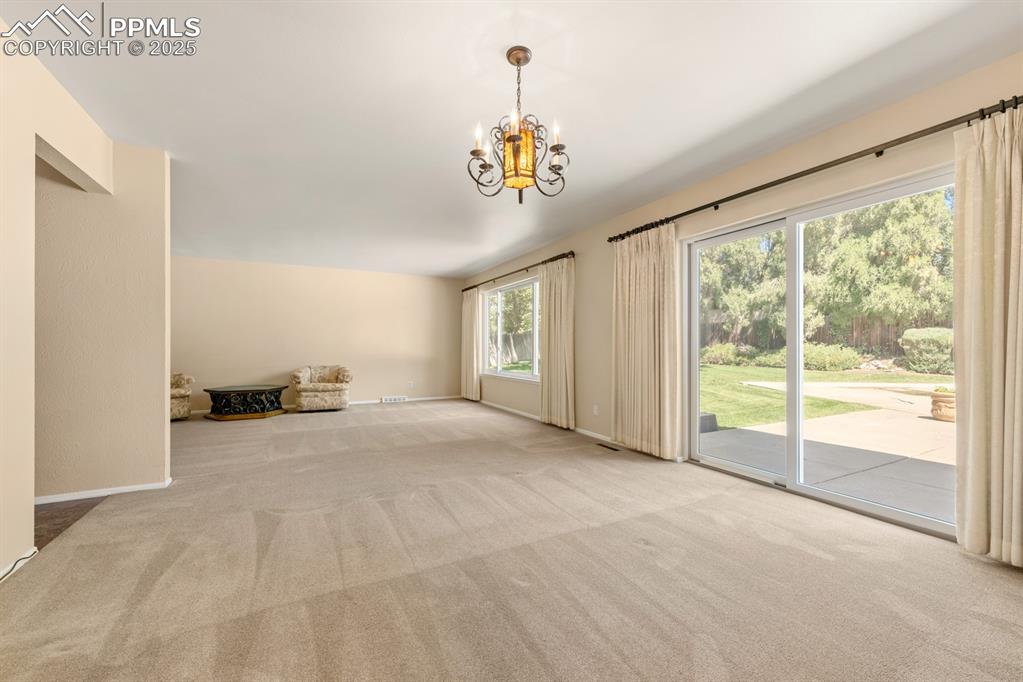 Image 16 of 50: Unfurnished living room with carpet floors and a chandelier