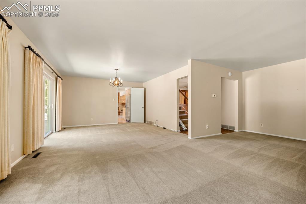 Image 17 of 50: Unfurnished room featuring carpet, a chandelier, and stairway