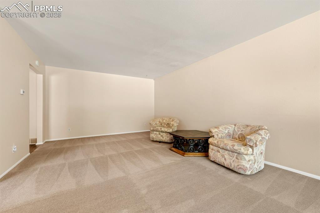 Image 18 of 50: Living area with carpet flooring