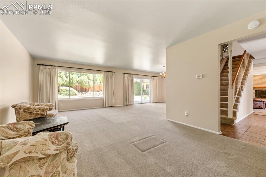 Image 19 of 50: Living area with carpet, a chandelier, and stairway