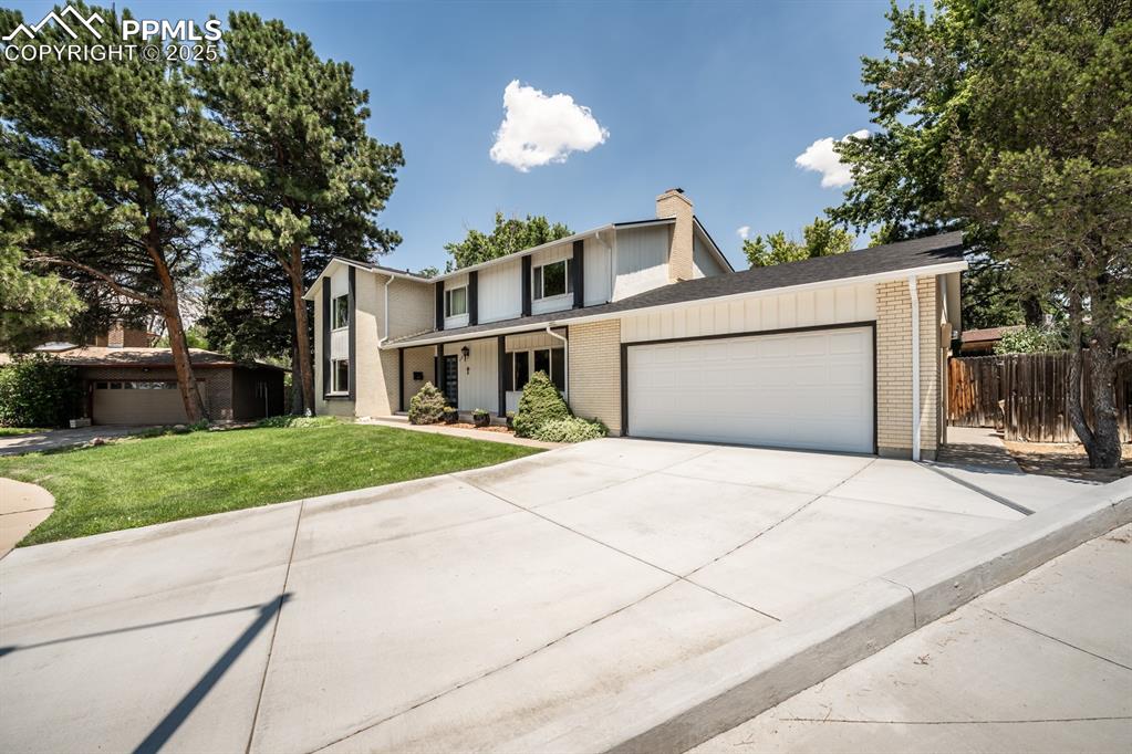 Image 2 of 50: View of front of property featuring brick siding, driveway, a garage, and a