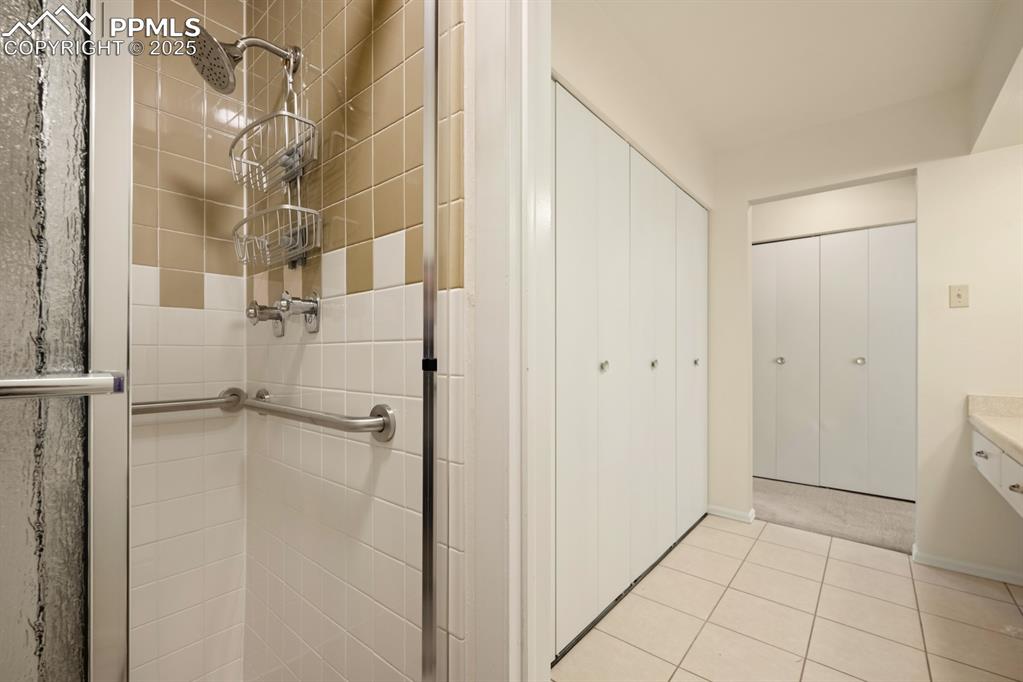 Image 32 of 50: Bathroom with a stall shower, light tile patterned flooring, and vanity