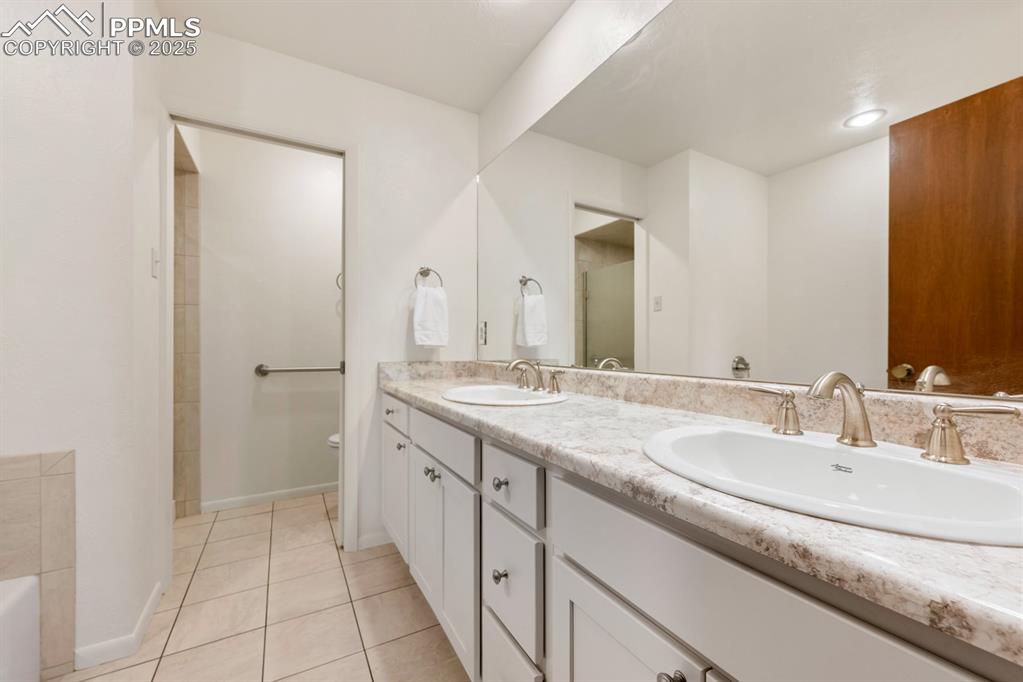 Image 35 of 50: Bathroom featuring double vanity, light tile patterned flooring, and a bath