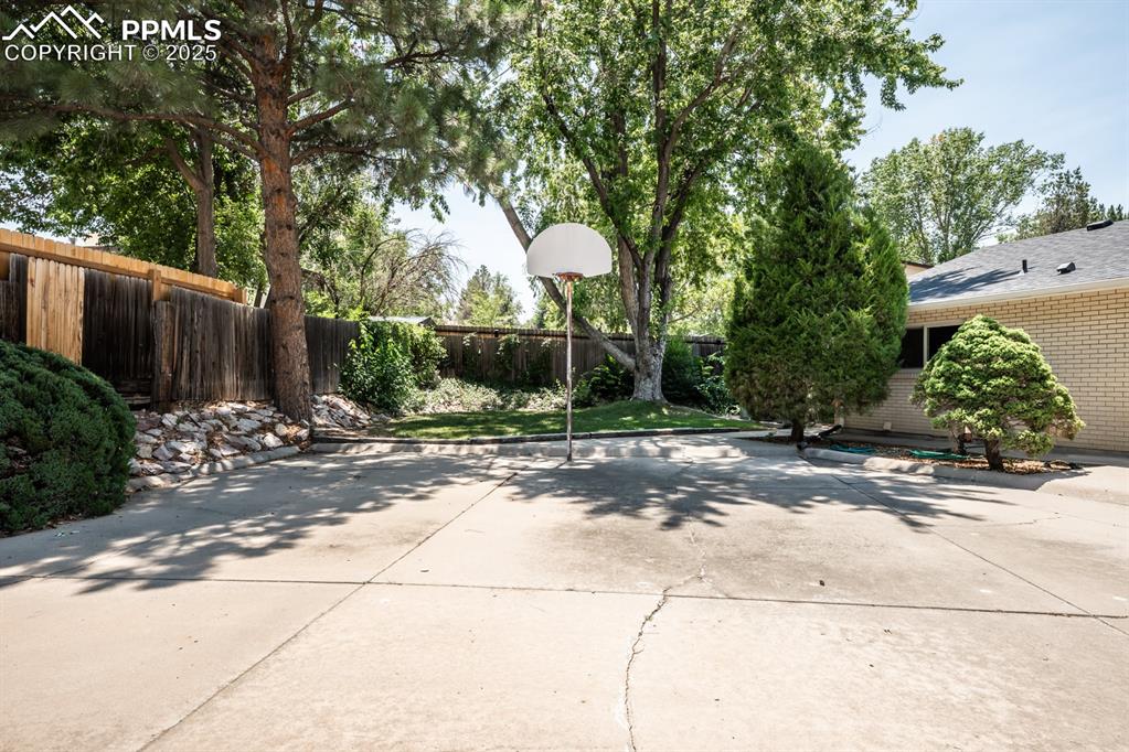 Image 50 of 50: View of basketball court with a fenced backyard and a patio area