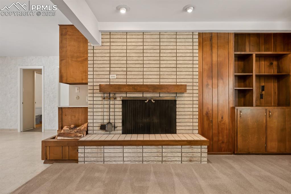 Image 9 of 50: Unfurnished living room with a fireplace and light carpet