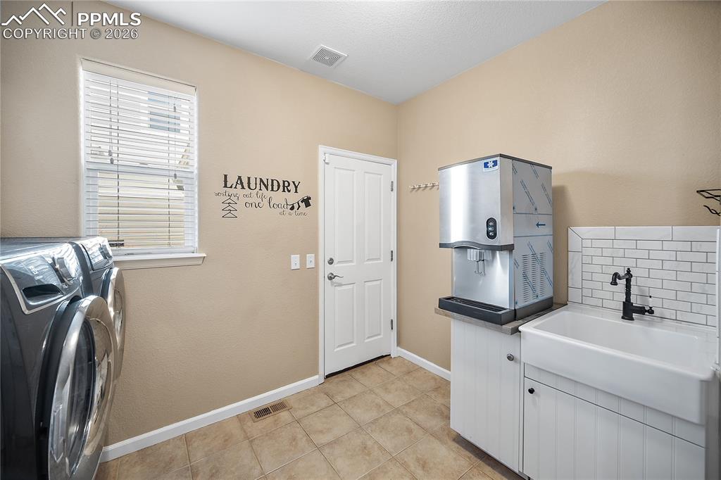 Image 17 of 48: Laundry room with sink and walk out. 