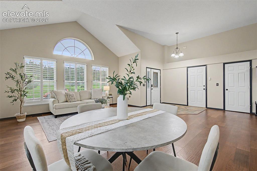 Image 10 of 50: Open-concept living area featuring vaulted ceilings, wood-finish flooring, 