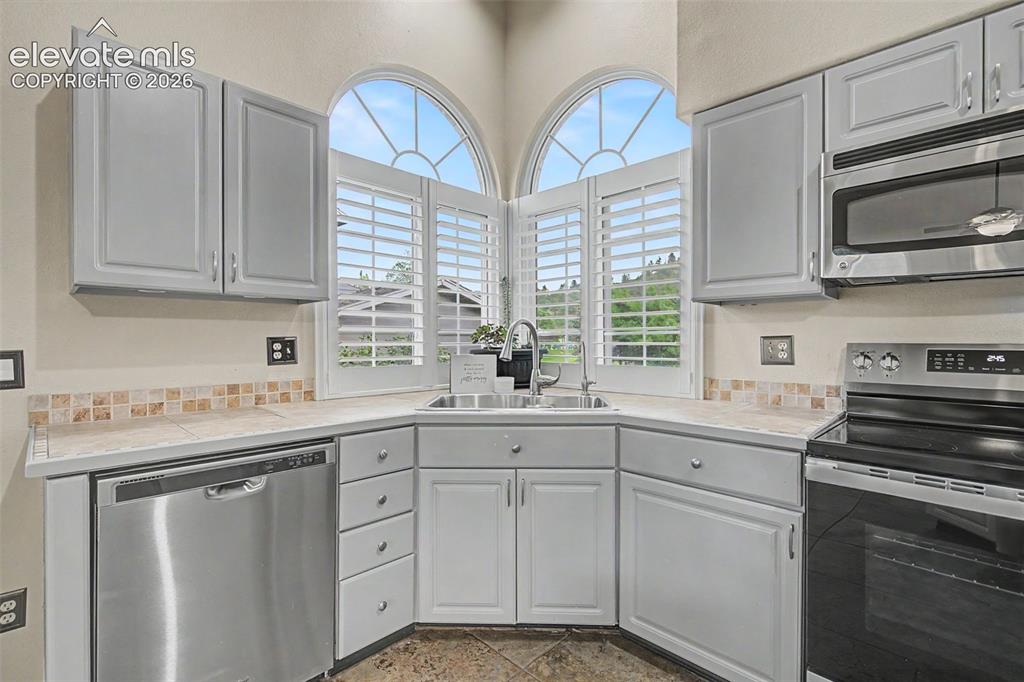Image 16 of 50: Kitchen featuring a corner sink, arched windows with plantation shutters, l