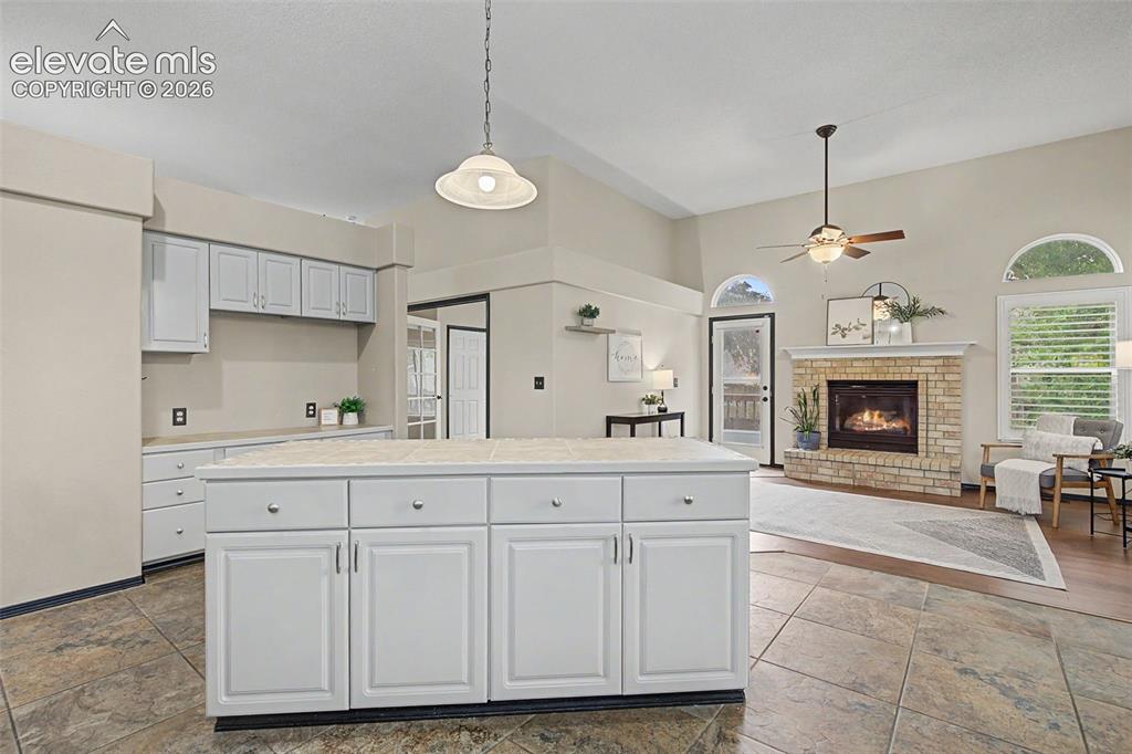 Image 17 of 50: Kitchen island with white cabinetry and a tiled countertop