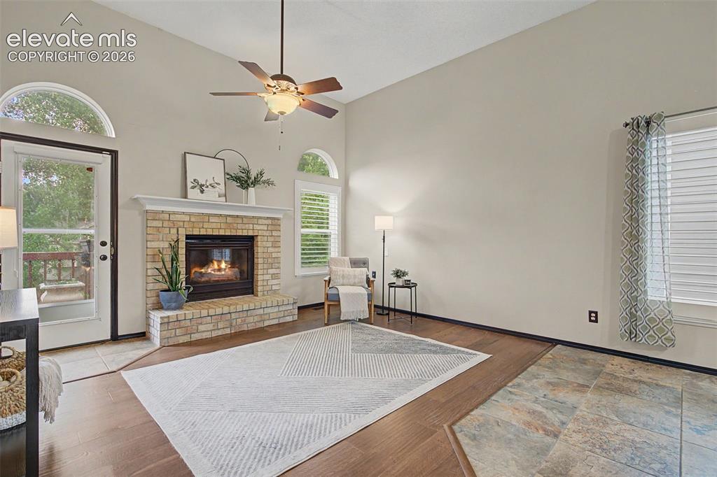 Image 21 of 50: Vaulted ceiling living area featuring a brick fireplace with mantel, ceilin