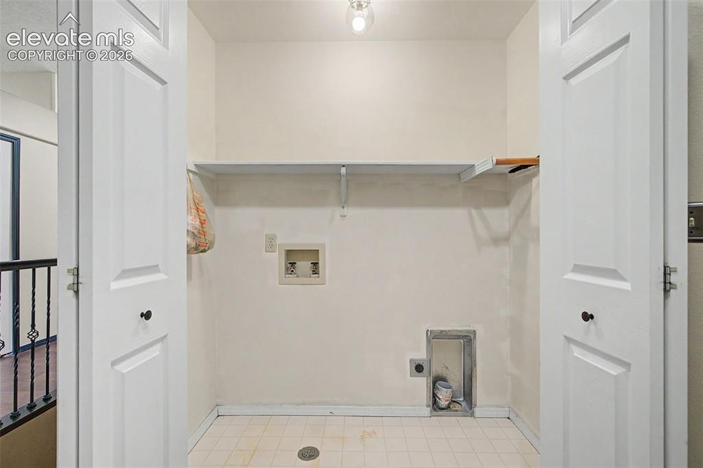 Image 26 of 50: Dedicated laundry closet featuring a built-in shelf, appliance hookups, and