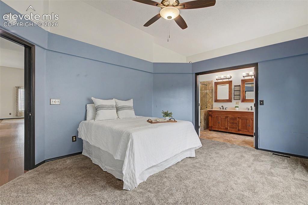 Image 28 of 50: Carpeted bedroom with a vaulted ceiling and ceiling fan