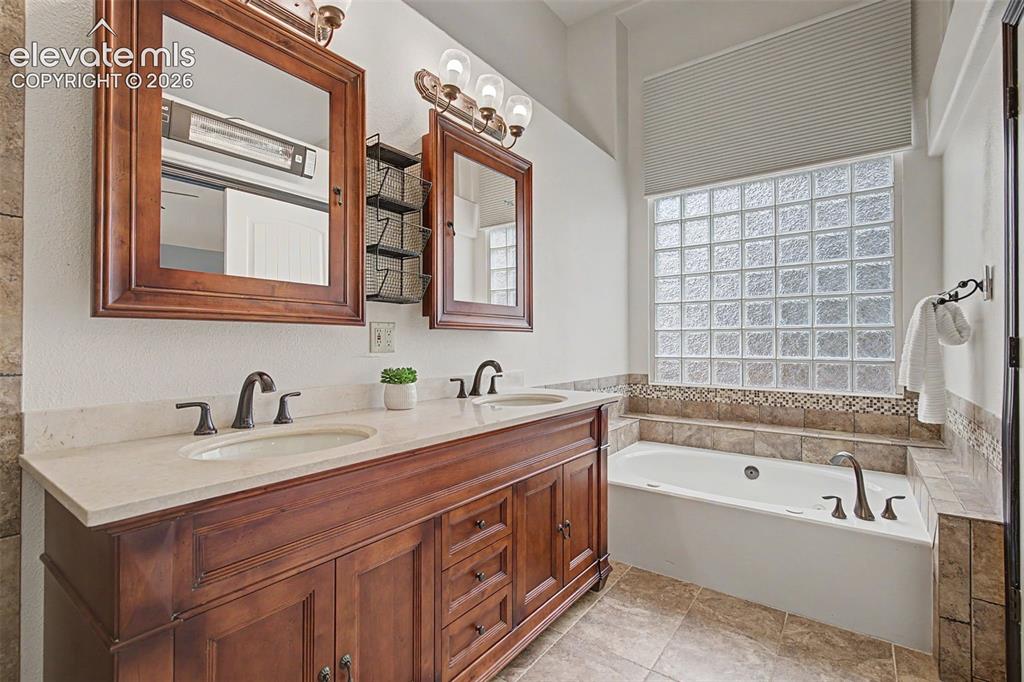 Image 31 of 50: Dual vanity with wood cabinetry, light-toned countertops, and bronze-finish