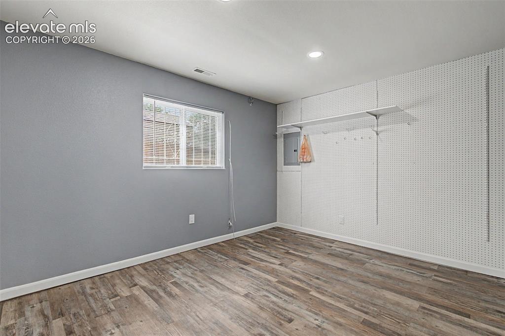 Image 35 of 50: Versatile room with wood-finish flooring, recessed lighting, and a window w
