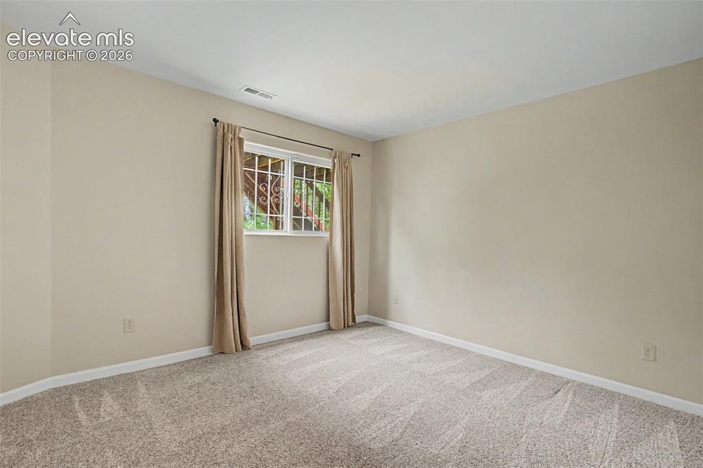 Image 36 of 50: Carpeted room with neutral wall paint and a window featuring decorative sec