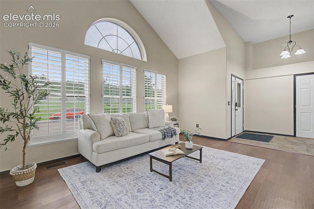 Image 4 of 50: Living room featuring vaulted ceilings, large arched window, three tall win