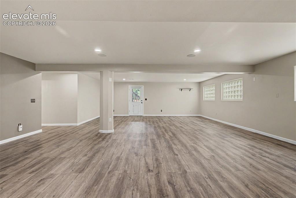 Image 41 of 50: Expansive room featuring wood-finish flooring, recessed lighting, and a whi