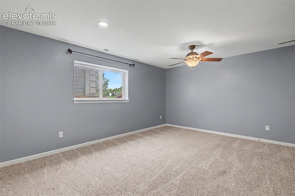 Image 44 of 50: Spacious room featuring neutral carpeting, a single window with a white fra