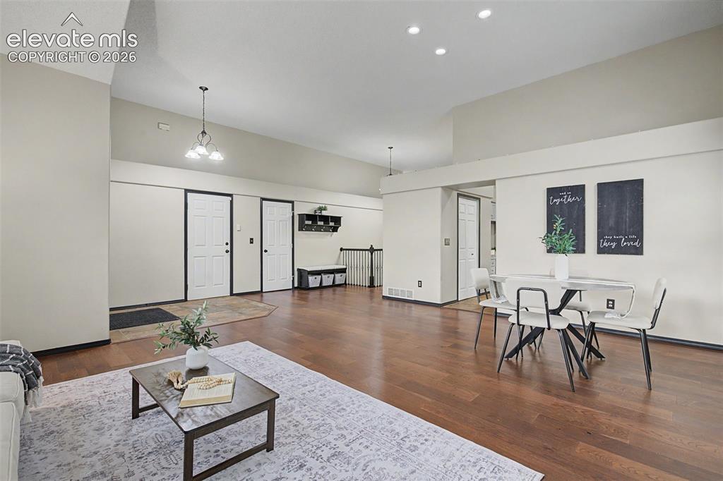 Image 6 of 50: Open-concept living area featuring wood-finish flooring, vaulted ceilings, 