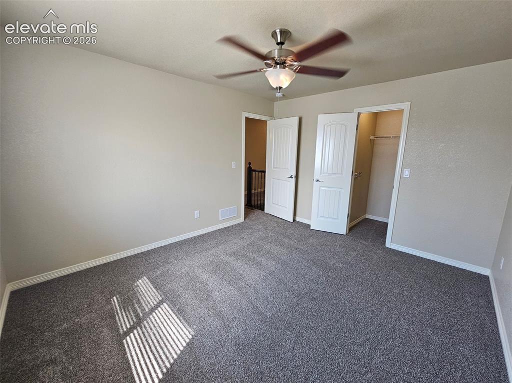 Image 12 of 31: Spacious room featuring neutral-toned walls, textured gray carpeting, a cei