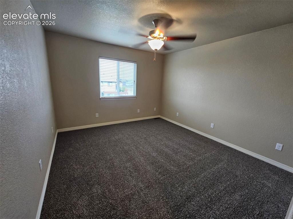 Image 22 of 31: Spacious room featuring neutral wall tones, dark textured carpeting, and a 