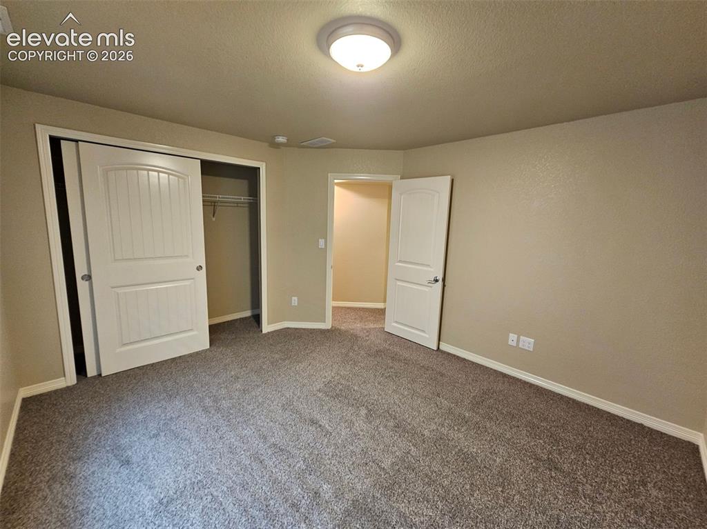 Image 28 of 31: Spacious room featuring neutral-toned walls, textured carpeting, and white 