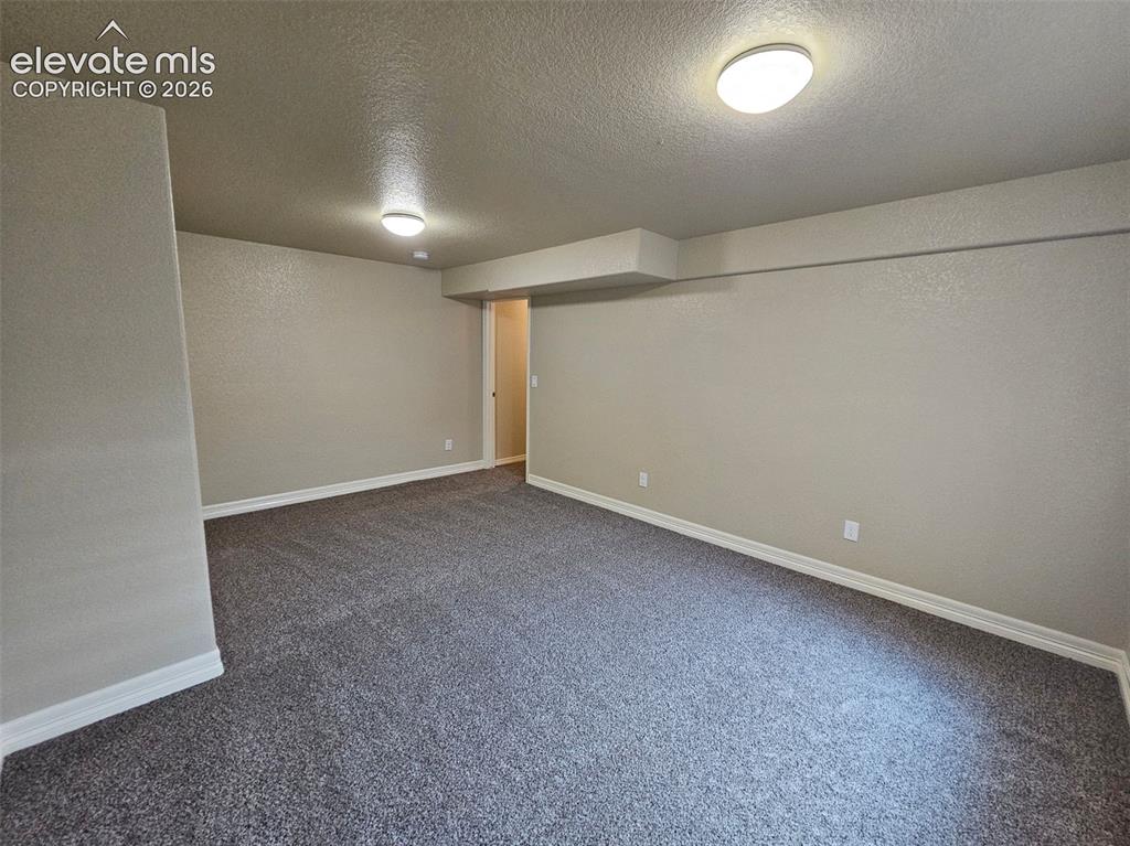 Image 31 of 31: Spacious room featuring neutral-toned walls, textured gray carpeting, white