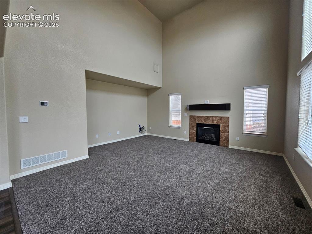 Image 5 of 31: Spacious living area featuring high vaulted ceilings, plush grey carpeting,