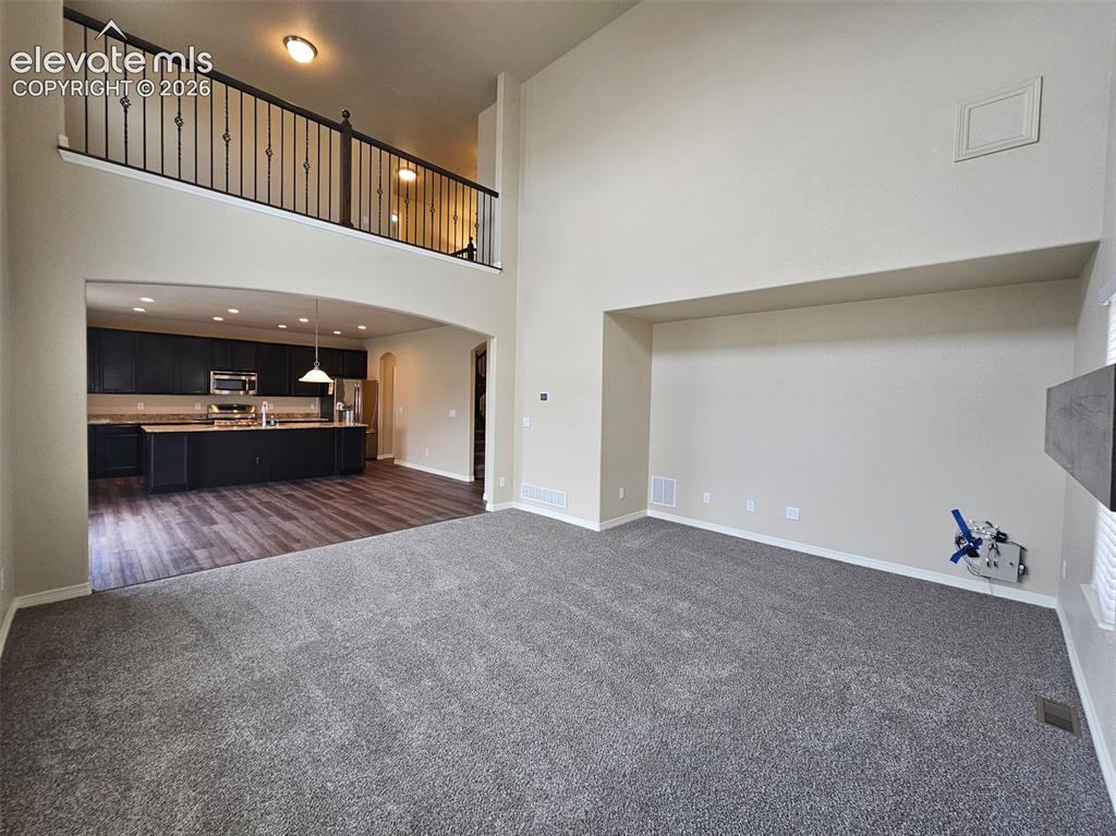 Image 6 of 31: Spacious living area featuring high ceilings and a second-story overlook wi