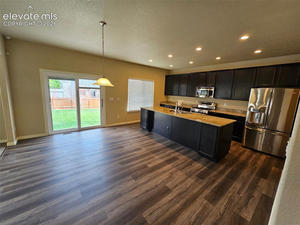 Image 7 of 31: Open-concept kitchen and dining area featuring wood-finish flooring, dark c