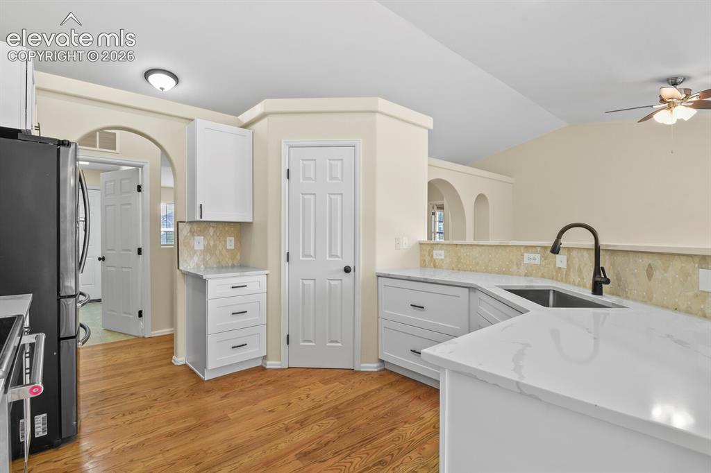 Image 13 of 48: Updated kitchen featuring white shaker cabinetry, quartz countertops, a bla
