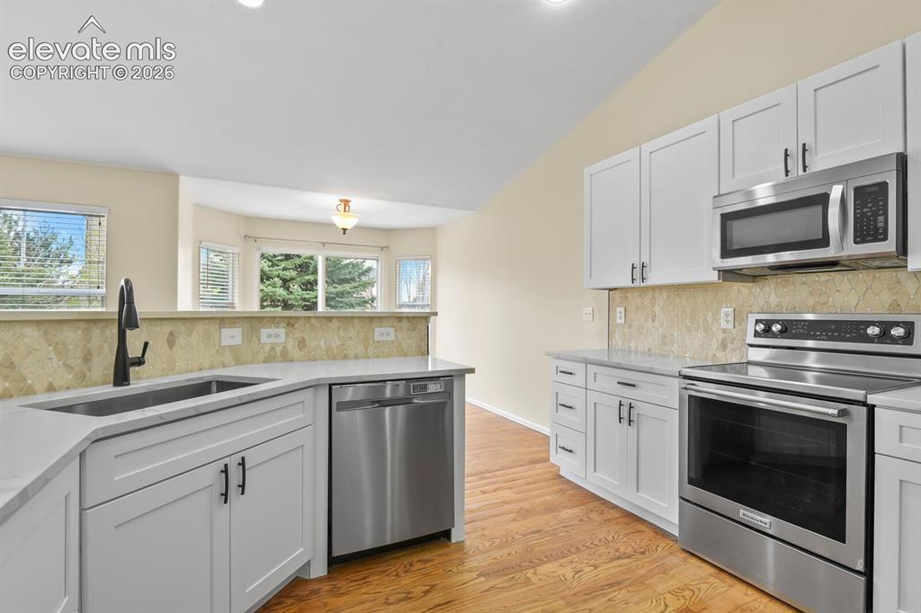 Image 15 of 48: Contemporary kitchen featuring white cabinetry, light-toned countertops, an