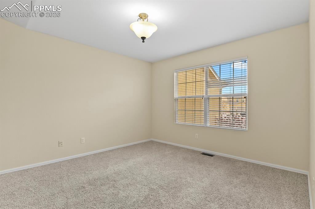 Image 16 of 43: Inviting room featuring a large window with blinds, neutral-toned walls, pl
