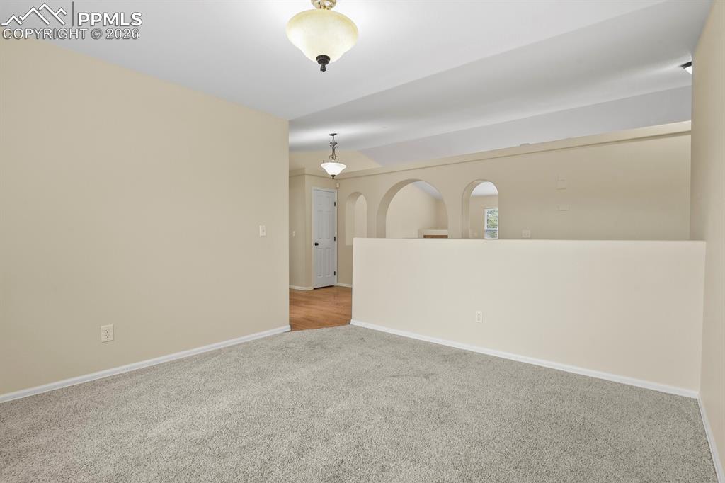 Image 17 of 43: Carpeted interior space with a vaulted ceiling and a built-in half wall