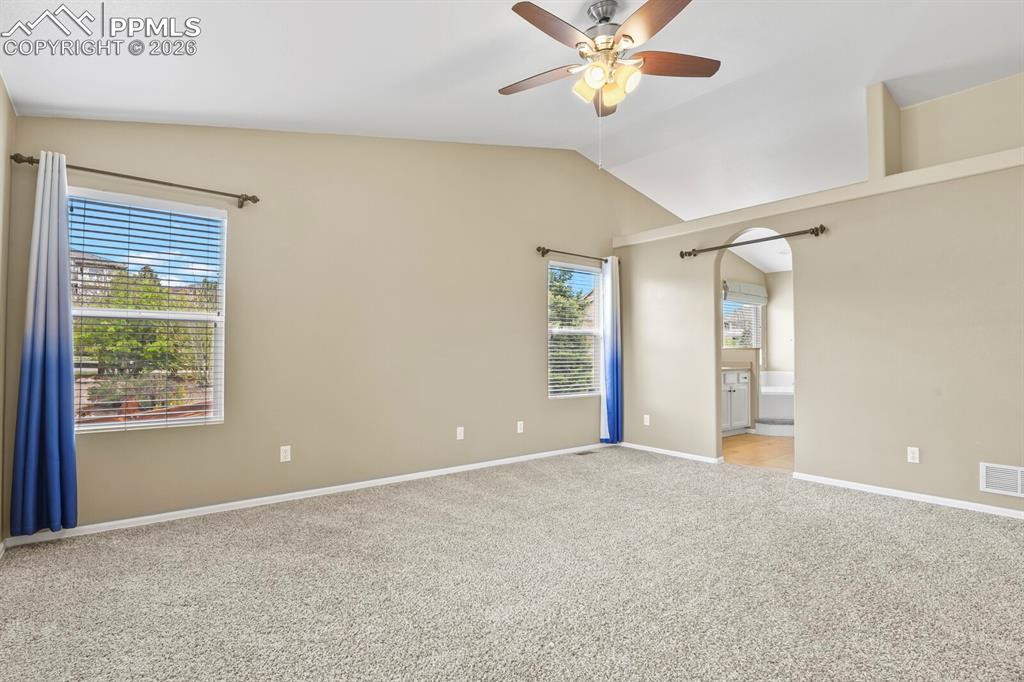 Image 19 of 43: Spacious room featuring vaulted ceilings, light tan walls, and wall-to-wall