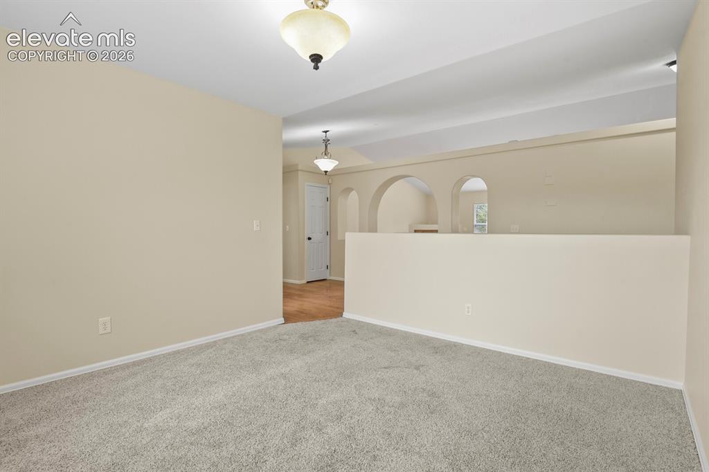 Image 19 of 48: Carpeted interior space with a vaulted ceiling and a built-in half wall