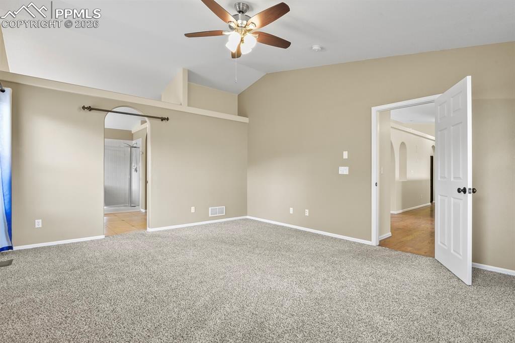 Image 20 of 43: Spacious room featuring vaulted ceilings, Ceiling Fan and neutral-toned wal