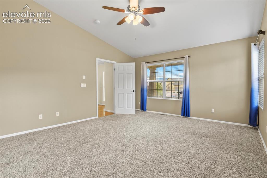 Image 20 of 48: Spacious room featuring vaulted ceilings, neutral wall tones, and plush car