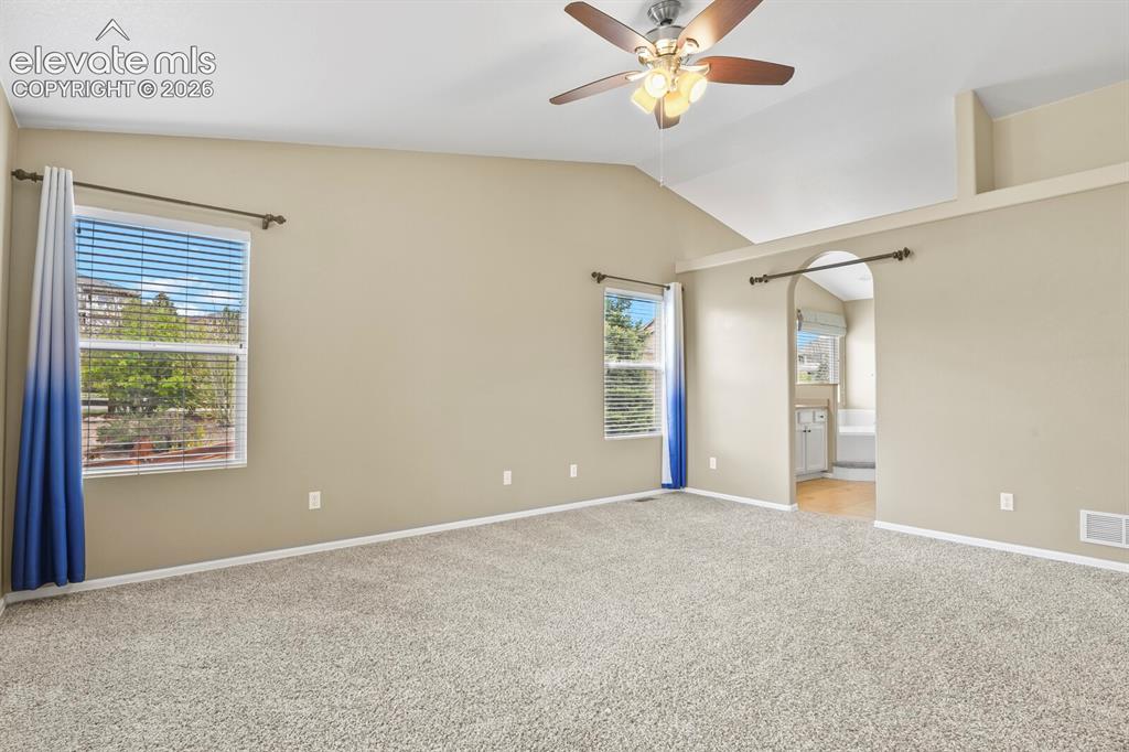 Image 21 of 48: Spacious room featuring vaulted ceilings, light tan walls, and wall-to-wall