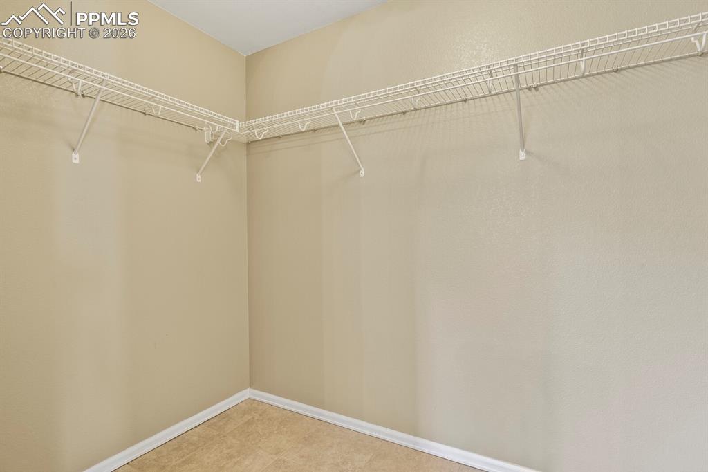 Image 22 of 43: Master Bedroom Walk in closet with wire shelving system and neutral wall pa
